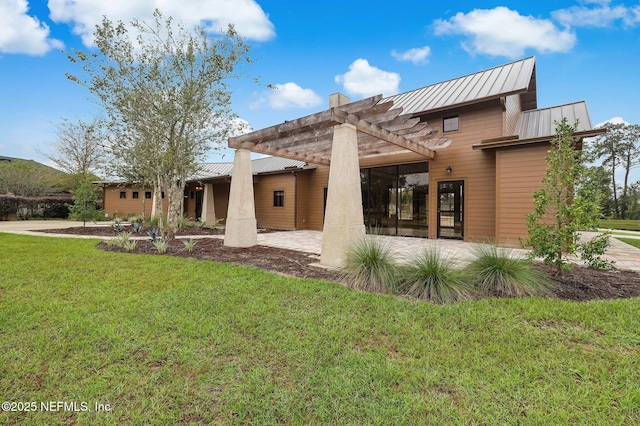 rear view of property featuring a standing seam roof, metal roof, a pergola, and a yard