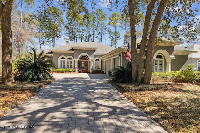 861998 N Hampton Club Way, Fernandina Beach, FL 32034 - mediterranean / spanish home featuring stucco siding, an attached garage, a chimney, and decorative driveway