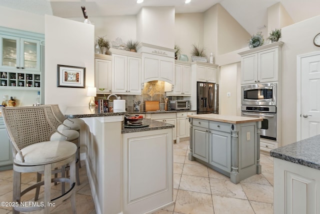 861998 N Hampton Club Way, Fernandina Beach, FL 32034 - kitchen featuring high vaulted ceiling, a toaster, decorative backsplash, a peninsula, and appliances with stainless steel finishes