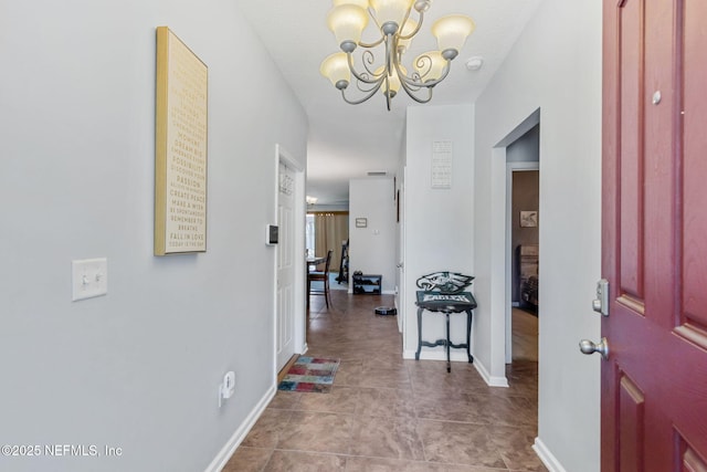 hallway with tile patterned flooring, an inviting chandelier, and baseboards