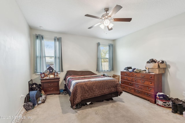 carpeted bedroom featuring multiple windows and ceiling fan