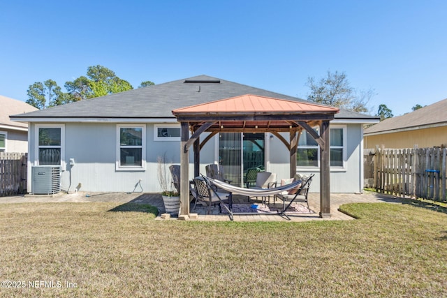 rear view of property featuring fence, a gazebo, a lawn, cooling unit, and a patio