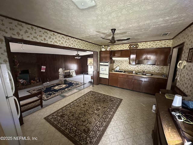 kitchen with white appliances, a ceiling fan, wallpapered walls, a textured ceiling, and tile patterned floors