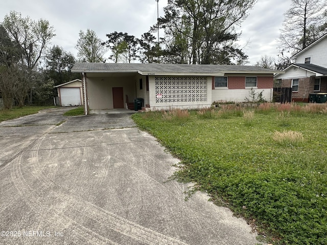 single story home featuring a carport, driveway, an outdoor structure, and brick siding