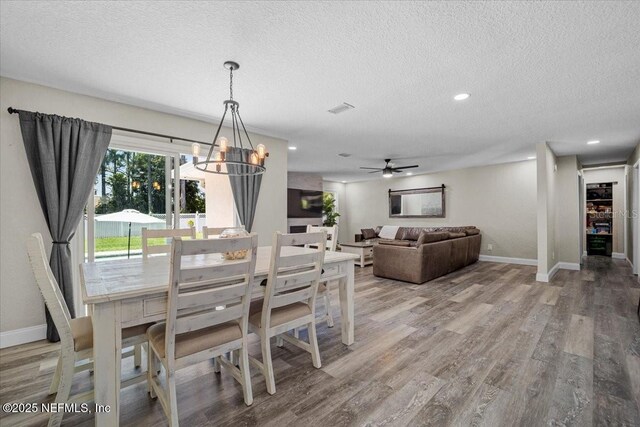 dining room with visible vents, light wood-style flooring, a textured ceiling, and baseboards