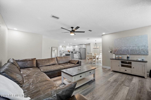 living area featuring light wood-type flooring, visible vents, and a textured ceiling