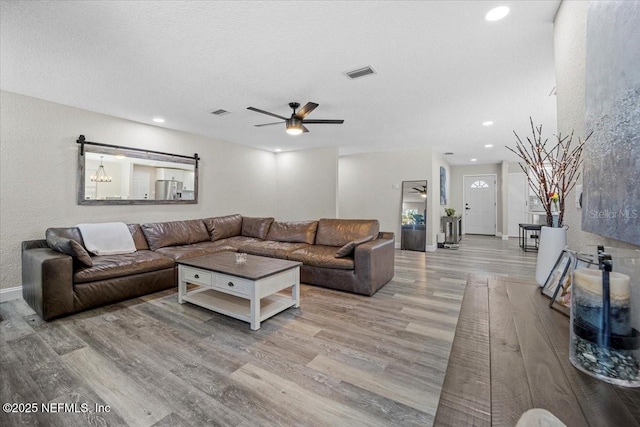 living area with recessed lighting, visible vents, and wood finished floors