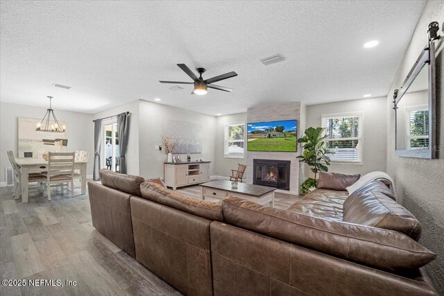 living room featuring visible vents, light wood-style floors, a fireplace, and a textured ceiling