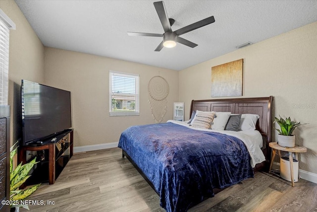 bedroom featuring a textured ceiling, wood finished floors, visible vents, and baseboards