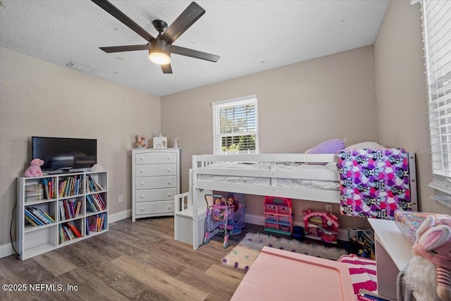 bedroom featuring visible vents, a ceiling fan, a textured ceiling, wood finished floors, and baseboards