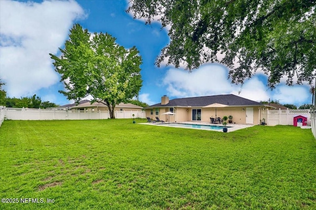 rear view of property with a patio, a fenced in pool, a yard, a fenced backyard, and stucco siding