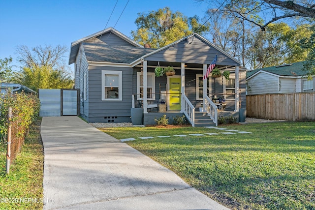 bungalow-style house with a front lawn, fence, covered porch, and crawl space