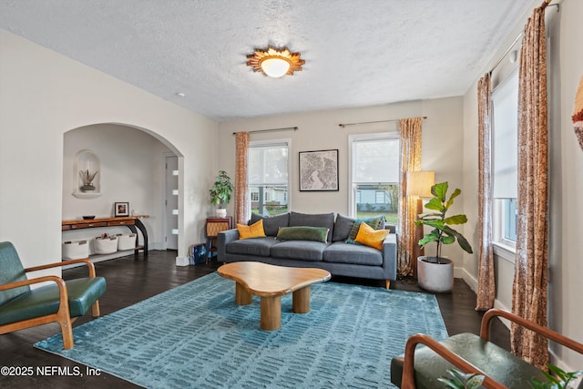 interior space with baseboards, wood finished floors, arched walkways, and a textured ceiling