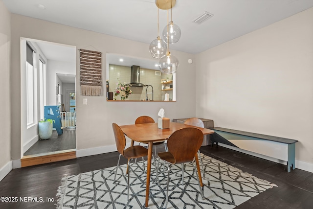 dining space featuring wood finished floors, visible vents, and baseboards