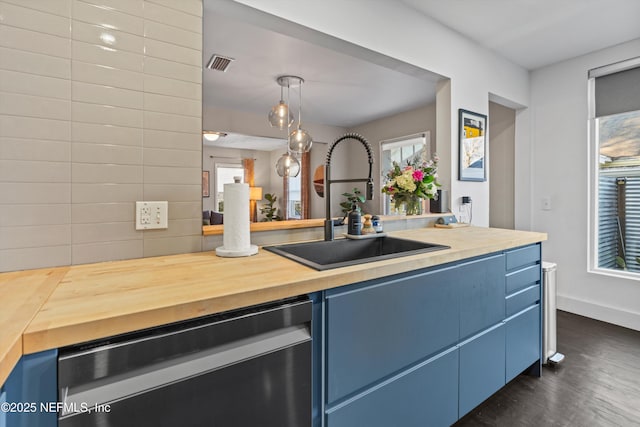 kitchen featuring a sink, blue cabinetry, butcher block counters, and stainless steel dishwasher