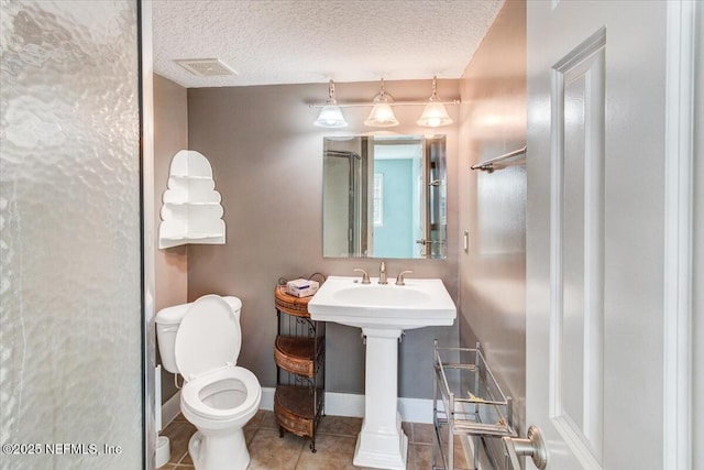 bathroom featuring baseboards, visible vents, a textured ceiling, tile patterned floors, and toilet