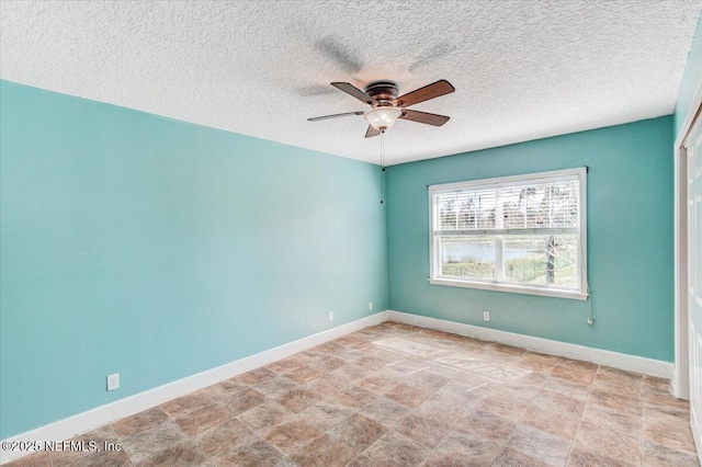 empty room featuring a textured ceiling, baseboards, and ceiling fan