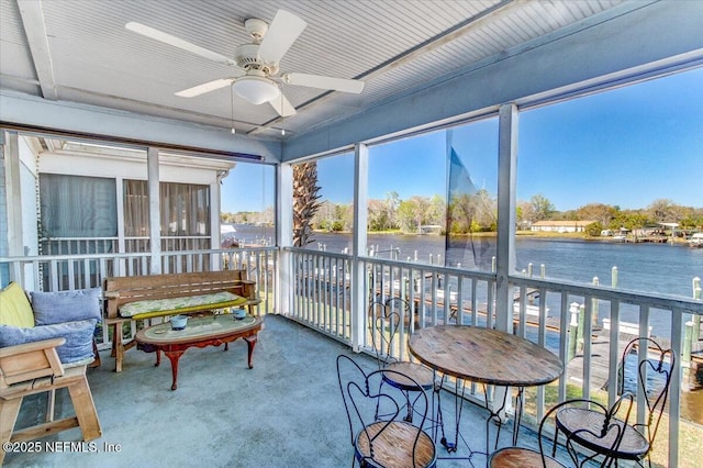 sunroom / solarium featuring a water view and a ceiling fan