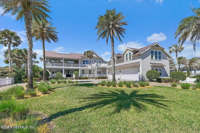 view of front of home featuring metal roof, a front yard, an attached garage, and fence