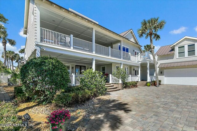 view of front facade featuring a balcony, covered porch, decorative driveway, and a garage