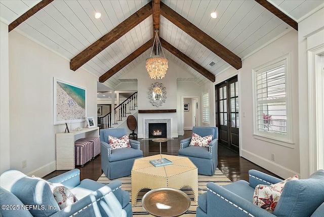 living room with lofted ceiling with beams, baseboards, a warm lit fireplace, and wood finished floors