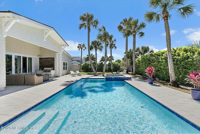 view of pool featuring an outdoor kitchen, a pool with connected hot tub, outdoor lounge area, and a patio