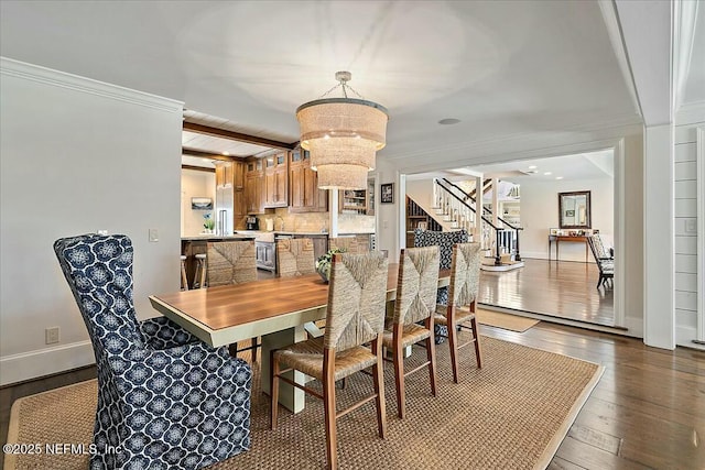 dining room with wood-type flooring, crown molding, baseboards, a chandelier, and stairs