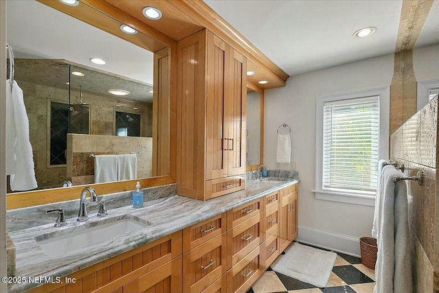 full bathroom featuring a tile shower, double vanity, baseboards, and a sink