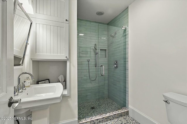 bathroom with a stall shower, toilet, baseboards, and a sink