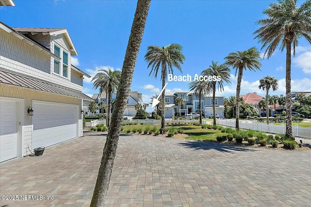 exterior space with a garage, decorative driveway, fence, and a residential view