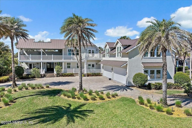 view of front of house with driveway, a front yard, and a balcony