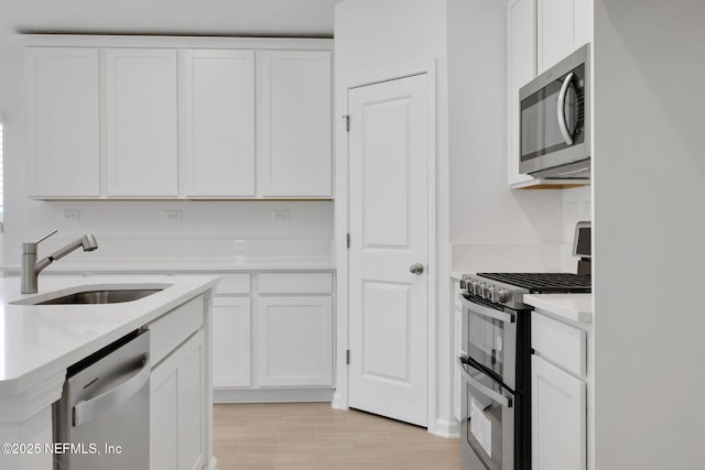 251 Pinzon Pl, Saint Augustine, FL 32095 - kitchen with appliances with stainless steel finishes, white cabinetry, light countertops, and light wood finished floors