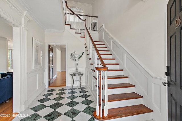 entrance foyer featuring a wealth of natural light, a decorative wall, stairway, and ornamental molding