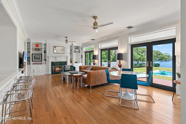 living area featuring visible vents, crown molding, ceiling fan, french doors, and light wood-style floors