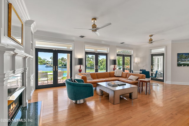 living area featuring a ceiling fan, crown molding, french doors, and a high end fireplace