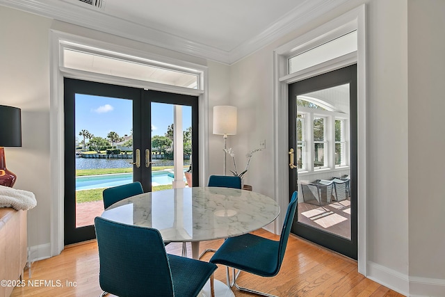 dining room featuring french doors, baseboards, crown molding, and light wood finished floors