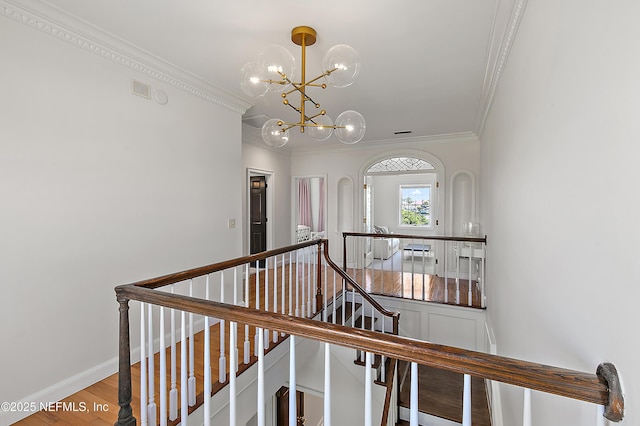 staircase with wood finished floors, visible vents, baseboards, an inviting chandelier, and ornamental molding