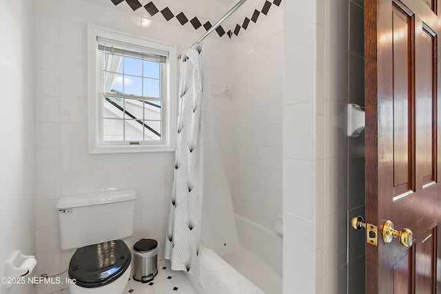 bathroom with tile patterned floors, shower / bath combo with shower curtain, toilet, and tile walls