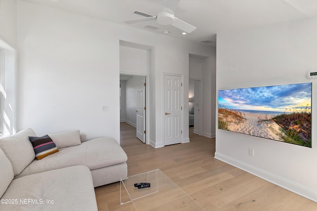 living area featuring visible vents, baseboards, a ceiling fan, and wood finished floors