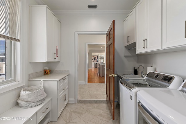 washroom featuring cabinet space, a sink, ornamental molding, washer and dryer, and marble finish floor