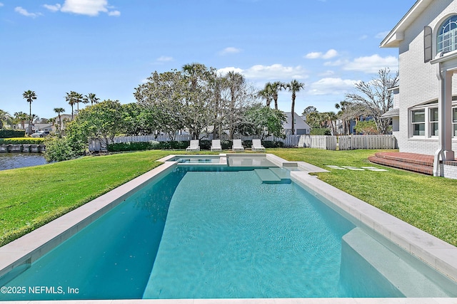 view of pool featuring a yard, a water view, a fenced backyard, and a pool with connected hot tub