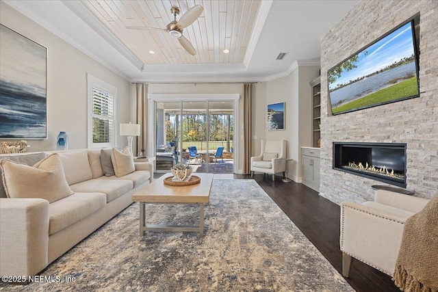 living area featuring built in shelves, wood ceiling, a tray ceiling, ornamental molding, and dark wood-style flooring