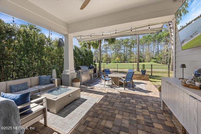 view of patio featuring area for grilling, an outdoor kitchen, fence, an outdoor living space with a fire pit, and ceiling fan