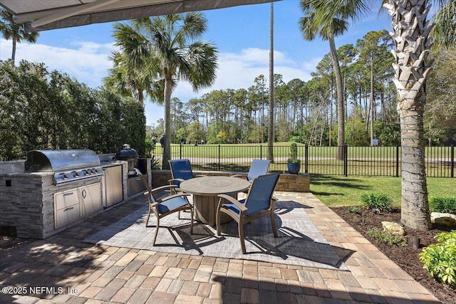 view of patio featuring outdoor dining area, area for grilling, an outdoor kitchen, and fence