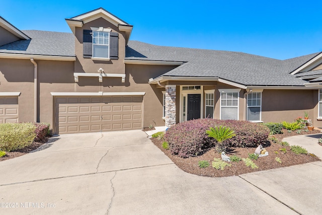 view of front of property with stucco siding, concrete driveway, and a shingled roof