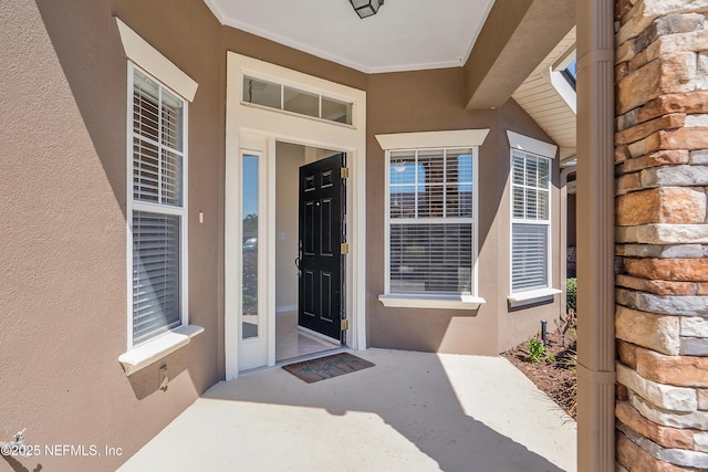 doorway to property with stucco siding and stone siding