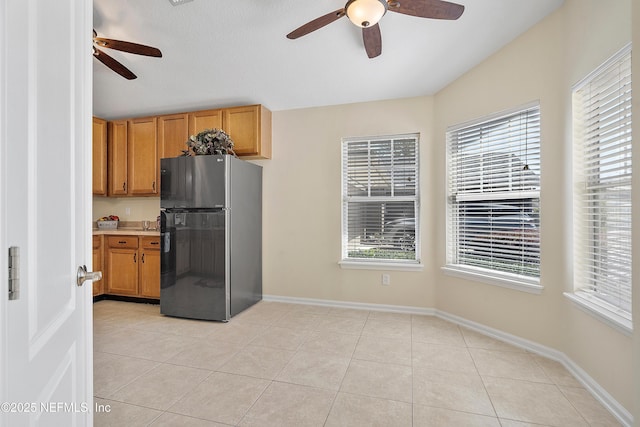 kitchen featuring light tile patterned flooring, a wealth of natural light, freestanding refrigerator, and a ceiling fan