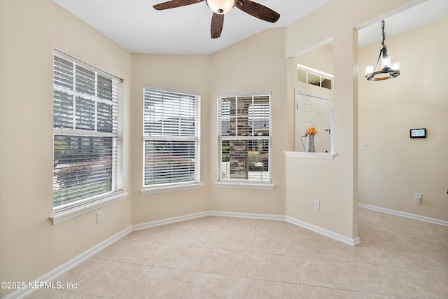 tiled empty room featuring baseboards, lofted ceiling, and a ceiling fan