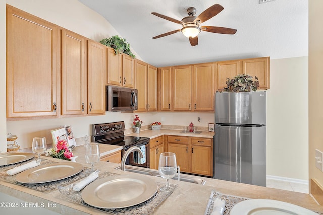 kitchen with light brown cabinets, a ceiling fan, appliances with stainless steel finishes, light countertops, and lofted ceiling