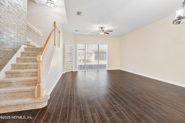 unfurnished living room featuring visible vents, stairway, dark wood-type flooring, and ceiling fan